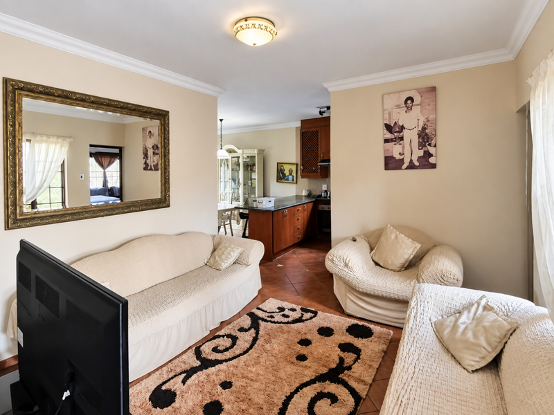 Open-plan living area featuring tiled flooring, cove cornicing, and a functional kitchen space with built-in cabinetry and countertops.