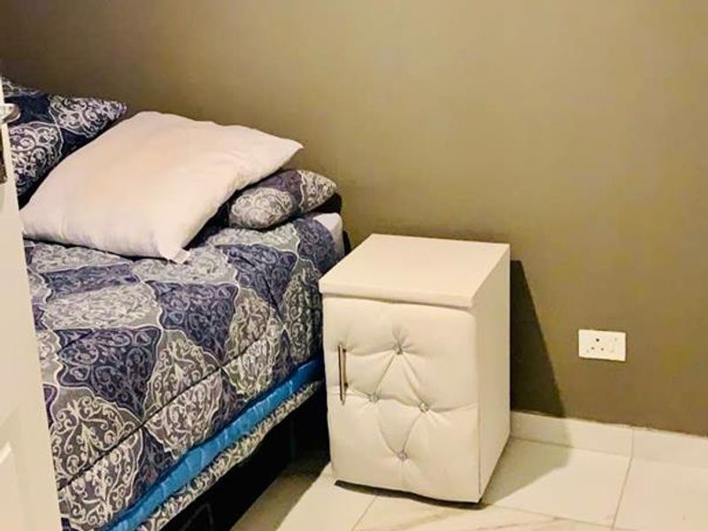 A bedroom featuring light-colored tiled flooring and neutral wall paint, providing a simple and functional sleeping space.
