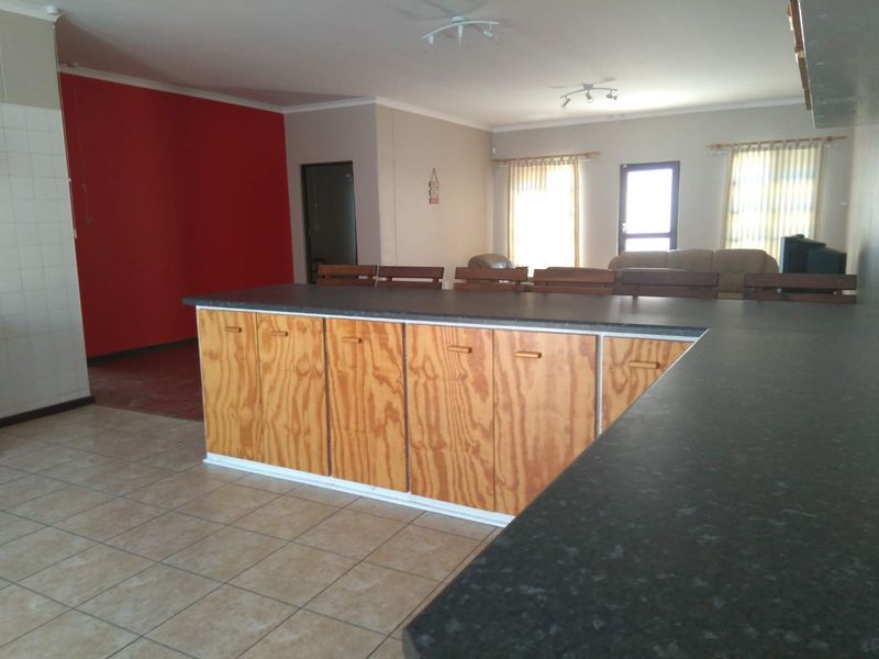 Spacious open-plan living and kitchen area featuring tiled flooring, extensive laminate cabinetry, and a functional layout suitable for modern updates.