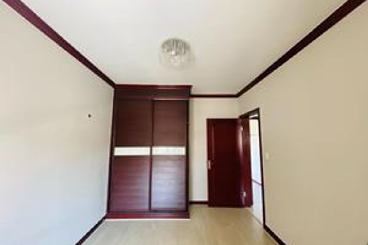 A bedroom featuring built-in dark wood sliding door wardrobes, matching door frame, and light-toned laminate flooring.
