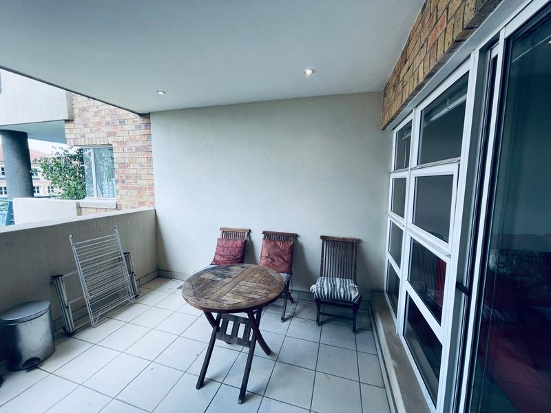 A covered balcony featuring tiled flooring, recessed lighting, and a sliding glass door, providing a functional outdoor space for relaxation.
