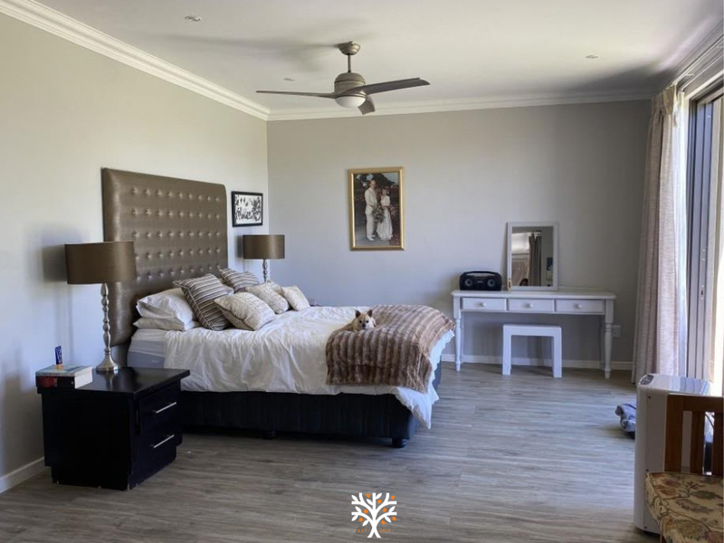 Spacious bedroom featuring modern laminate flooring, recessed lighting, a ceiling fan, and large sliding glass doors providing natural light.