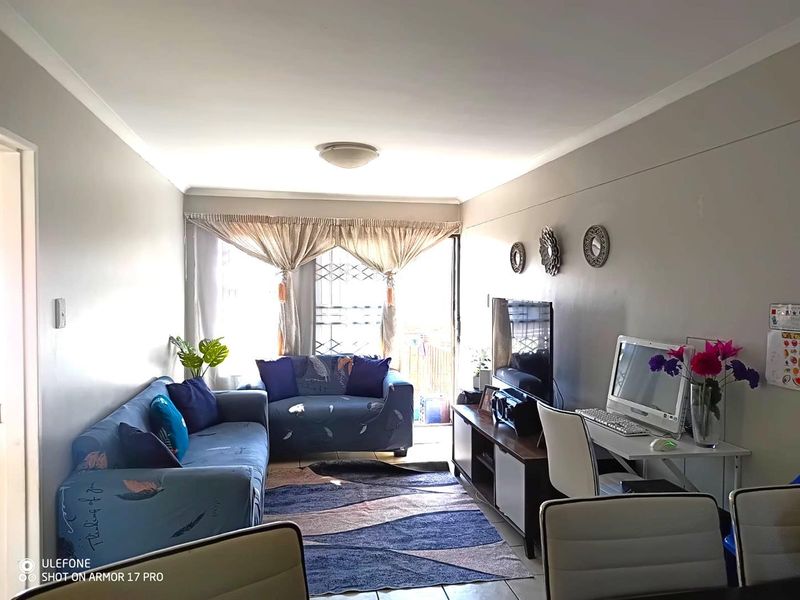 A functional living room featuring tiled flooring, cove cornicing, and a security gate leading to an outdoor area.