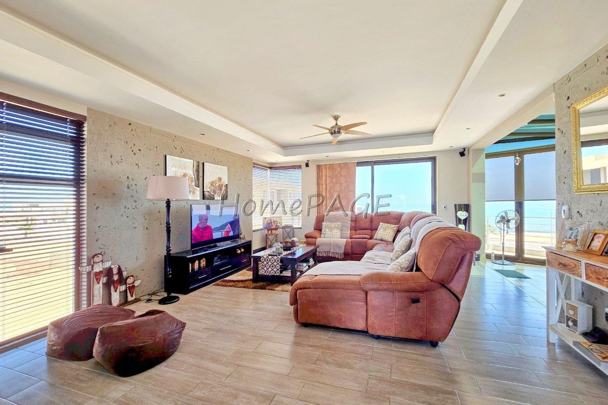 Spacious living room featuring a textured feature wall, recessed tray ceiling with a central fan, and large sliding doors leading to an outdoor area.
