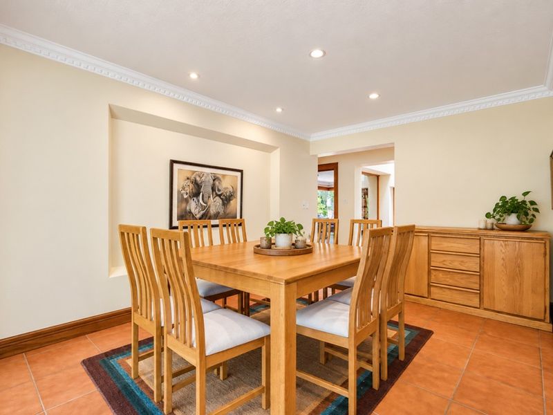 A well-maintained dining room featuring tiled flooring, recessed ceiling lighting, decorative cornice, and a built-in wall niche.