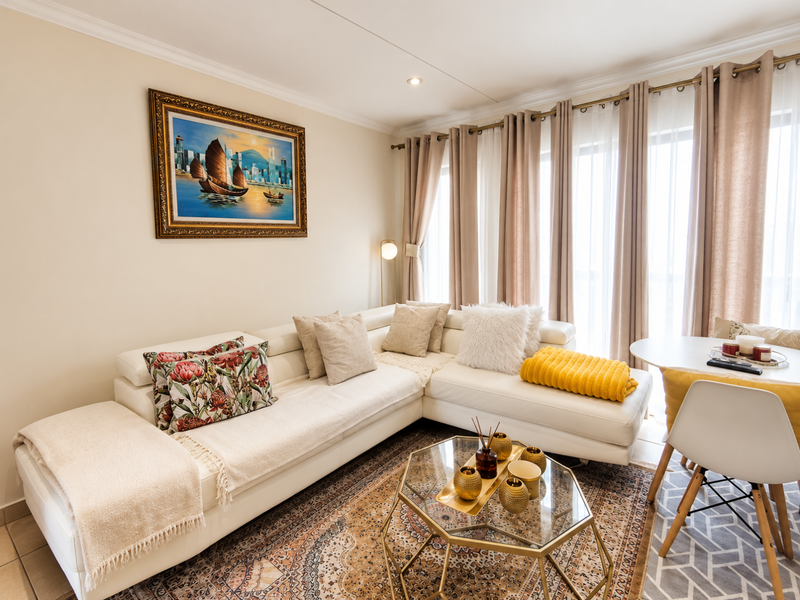 A bright and well-maintained living room featuring tiled flooring, recessed lighting, and large sliding glass doors providing ample natural light.