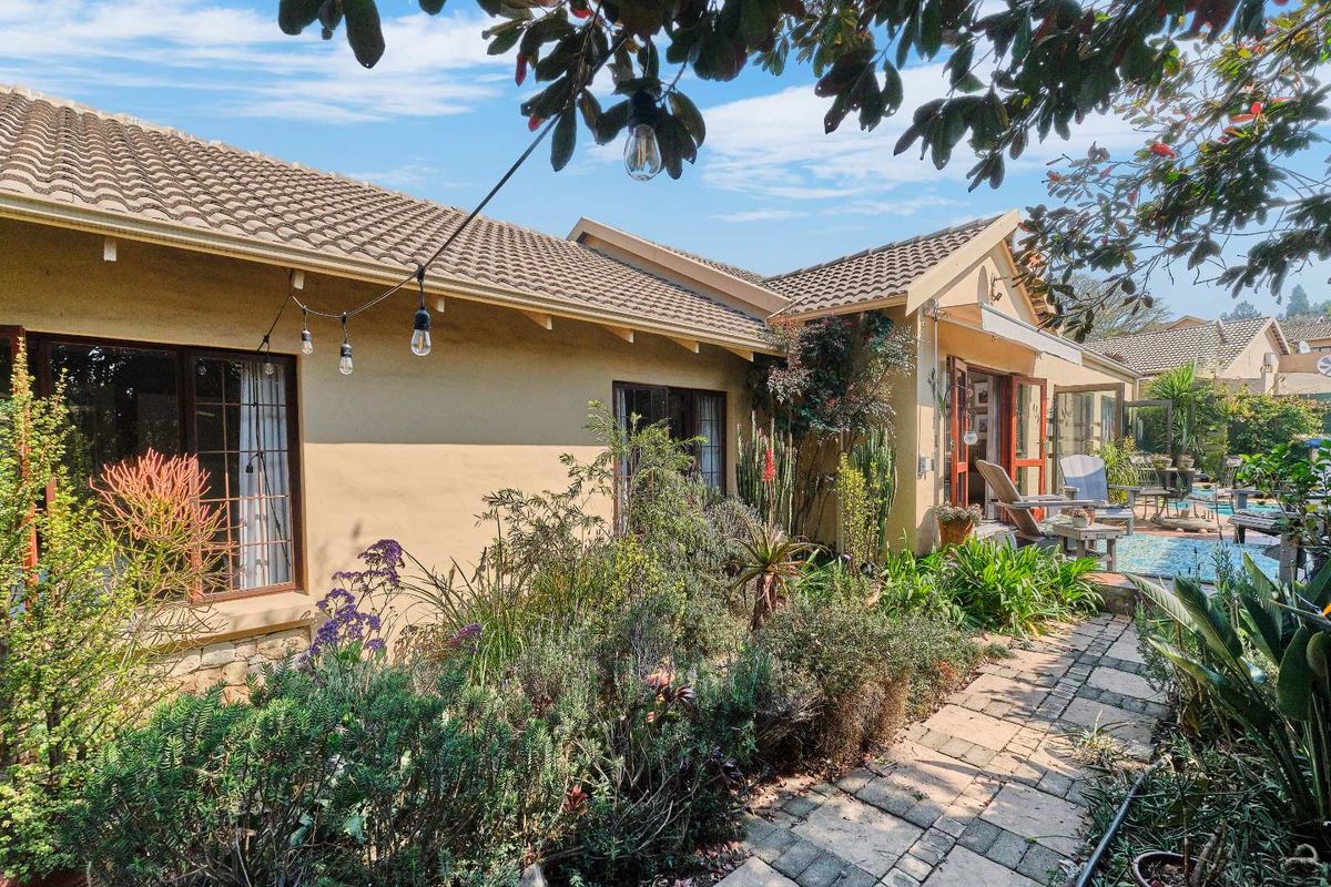 Rear view of the house featuring a paved garden path, tiled roof, and timber-framed french doors leading to the outdoor living area.