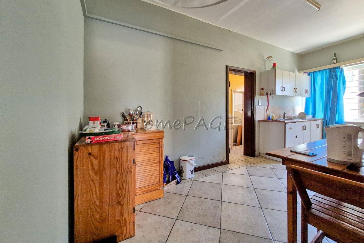 A functional kitchen area featuring tiled flooring, built-in cabinetry, and a doorway leading to an adjacent room.