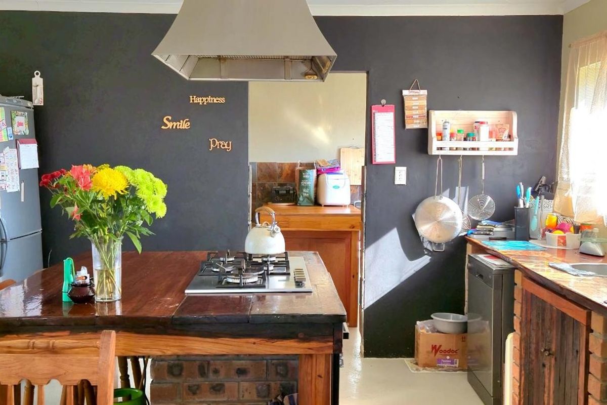 A rustic-style kitchen featuring a central timber island with a built-in gas hob, stainless steel extractor fan, and brick-based cabinetry.