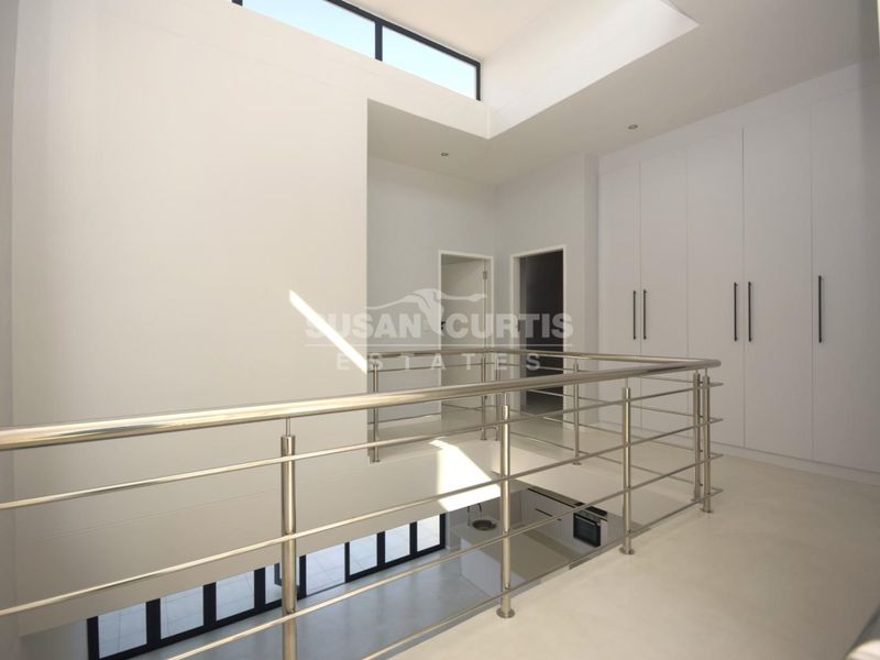 Spacious upper-level landing featuring a modern stainless steel balustrade, ample built-in storage, and high ceilings with clerestory windows providing abundant natural light.