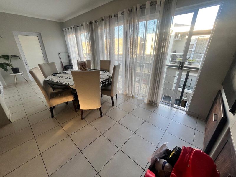 A bright dining area featuring large sliding glass doors that provide access to a balcony and allow for ample natural light.