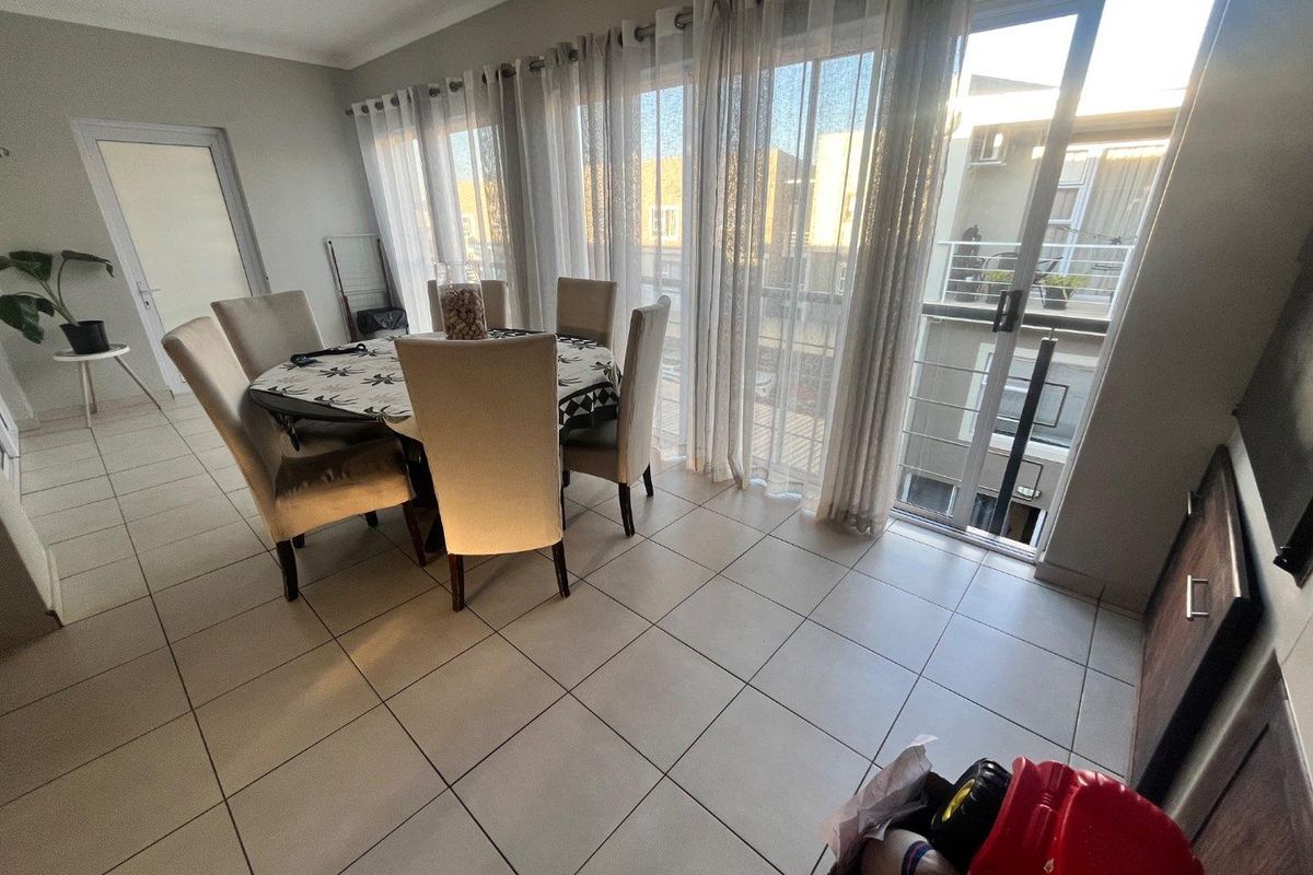 A bright dining area featuring large sliding glass doors that provide access to a balcony and allow for ample natural light.