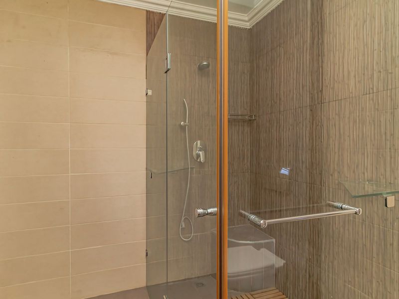 A modern bathroom shower area featuring a glass enclosure, tiled walls with textured accents, and a handheld shower fixture.