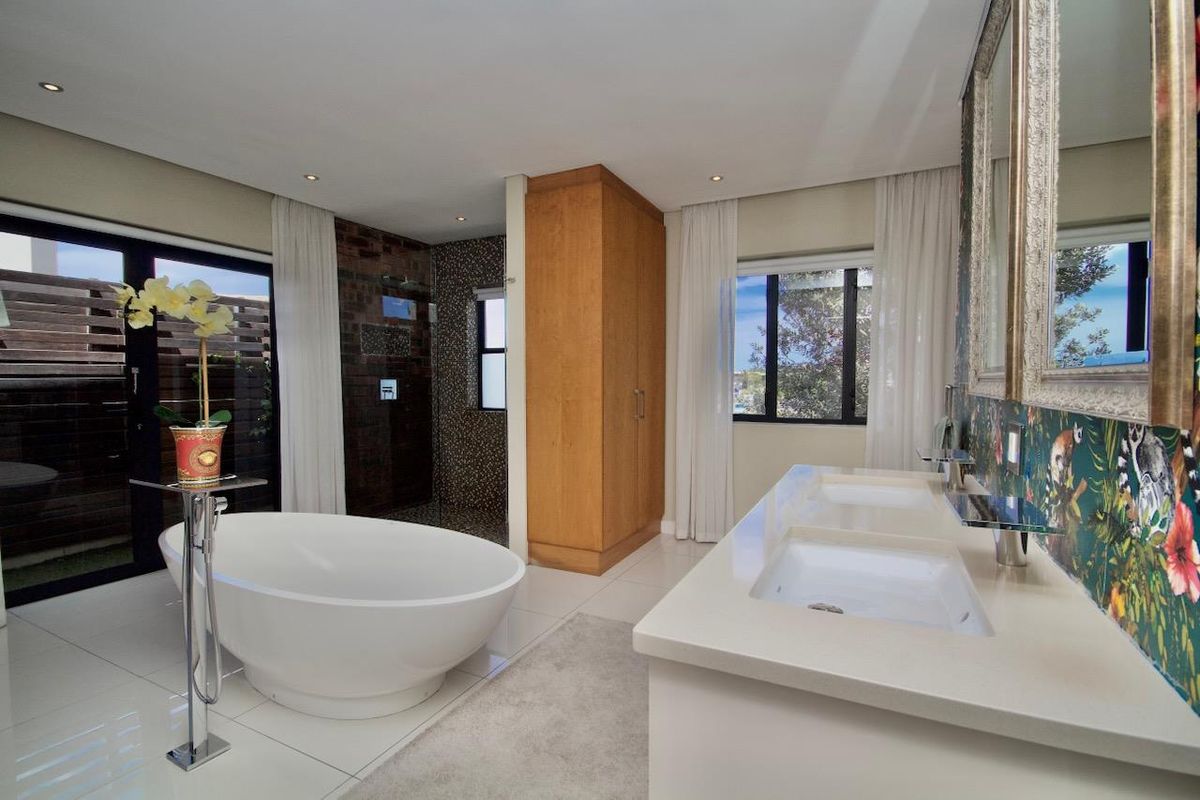 Modern en-suite bathroom featuring a freestanding bathtub, double vanity with stone countertop, and a walk-in shower with tiled finishes.