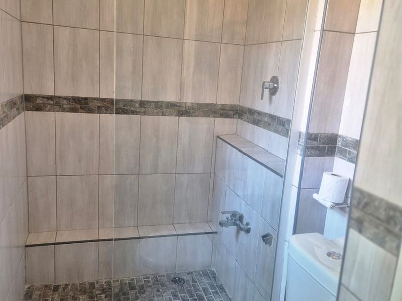 Modern bathroom featuring a walk-in shower with a rain shower head, built-in bench, and neutral tiled finishes.
