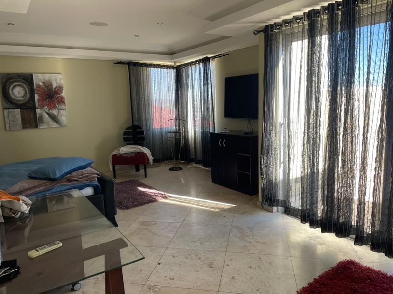 Spacious bedroom featuring tiled flooring, recessed ceiling lighting, and large sliding glass doors that provide ample natural light.