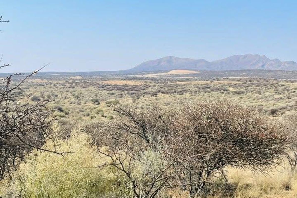 A scenic landscape view overlooking expansive natural terrain with distant mountain ranges under a clear blue sky.