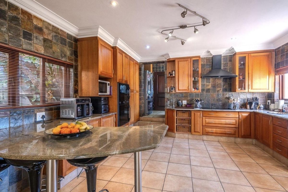 Spacious kitchen featuring timber cabinetry, granite countertops, a breakfast bar, and a built-in oven with an extractor fan.