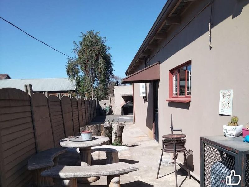 Rear exterior area featuring a concrete patio, boundary wall, and external building fixtures, providing a functional outdoor space for the cottage.