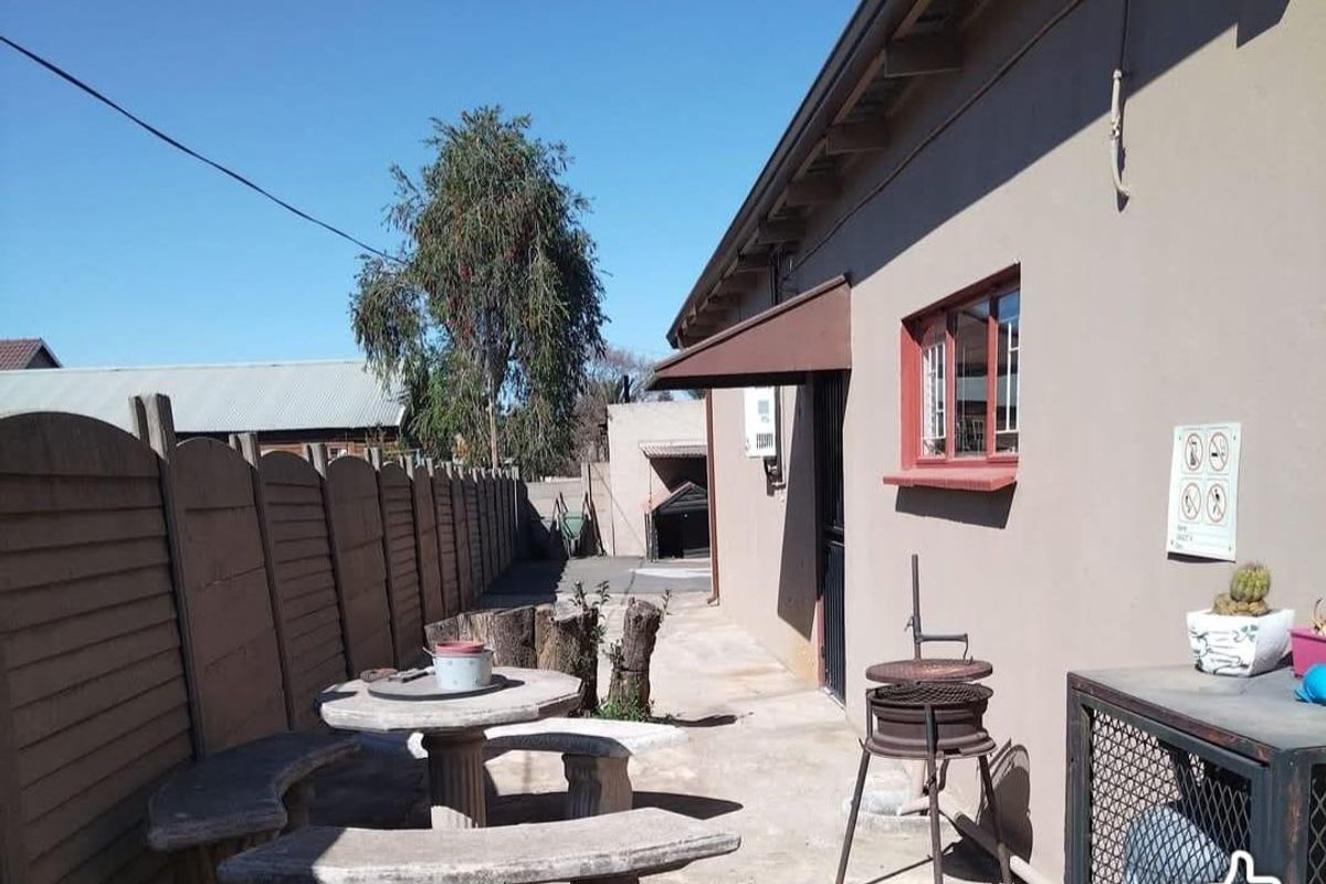 Rear exterior area featuring a concrete patio, boundary wall, and external building fixtures, providing a functional outdoor space for the cottage.