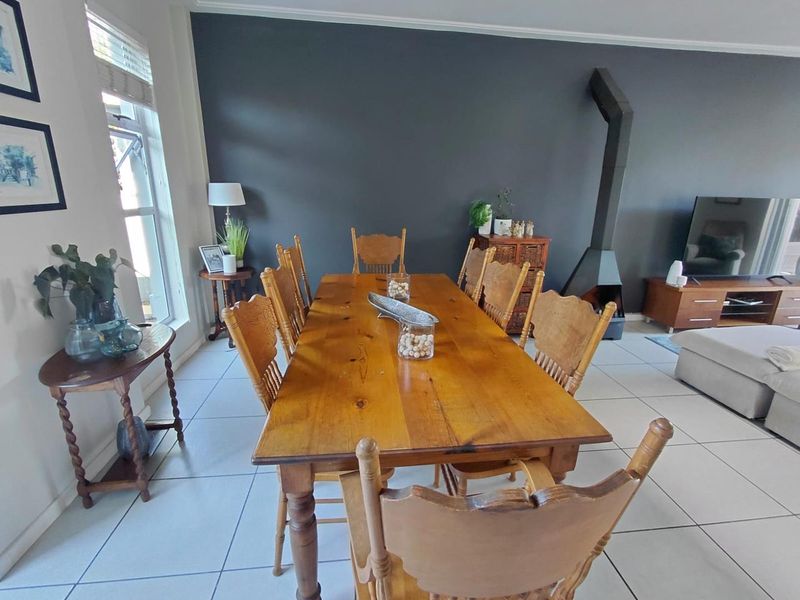 A spacious dining area featuring tiled flooring, a modern dark accent wall, and a prominent freestanding fireplace, creating a cozy and functional living space.