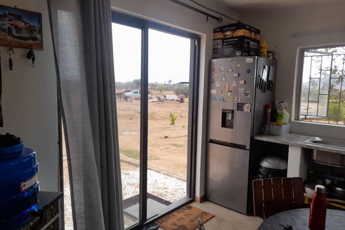 A functional kitchen area featuring a stainless steel refrigerator, stone countertop, and a sliding glass door providing direct access to the exterior.