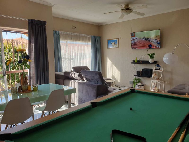 Open plan living and dining area featuring tiled flooring, a ceiling fan, and large sliding glass doors providing natural light.