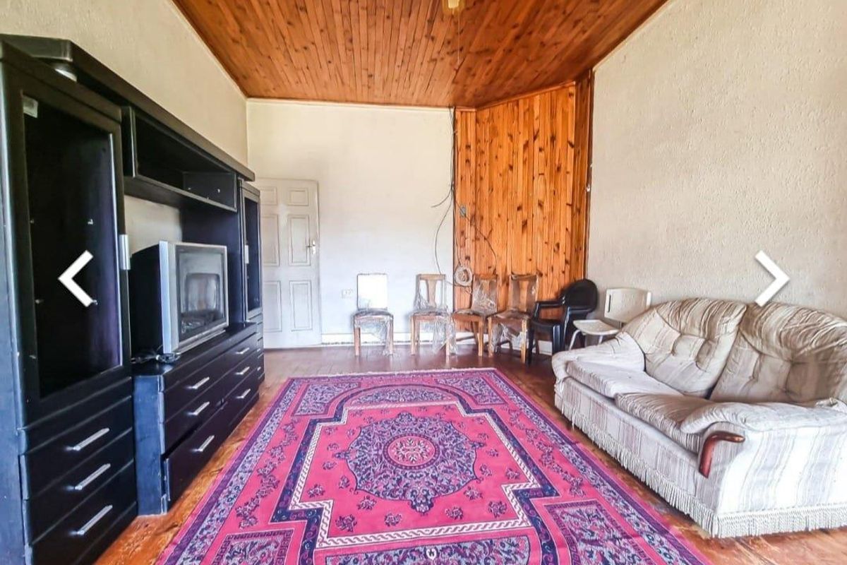 A living room featuring timber-clad ceilings and walls, wooden flooring, and a traditional layout.
