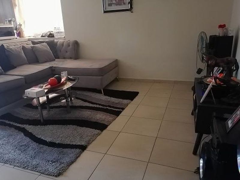 A living room area featuring neutral tiled flooring and a standard layout, suitable for comfortable family living.