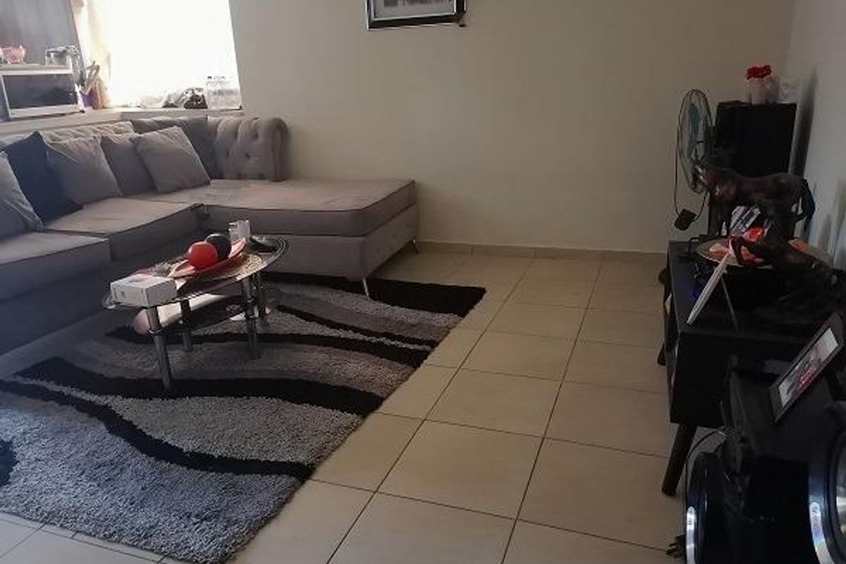 A living room area featuring neutral tiled flooring and a standard layout, suitable for comfortable family living.