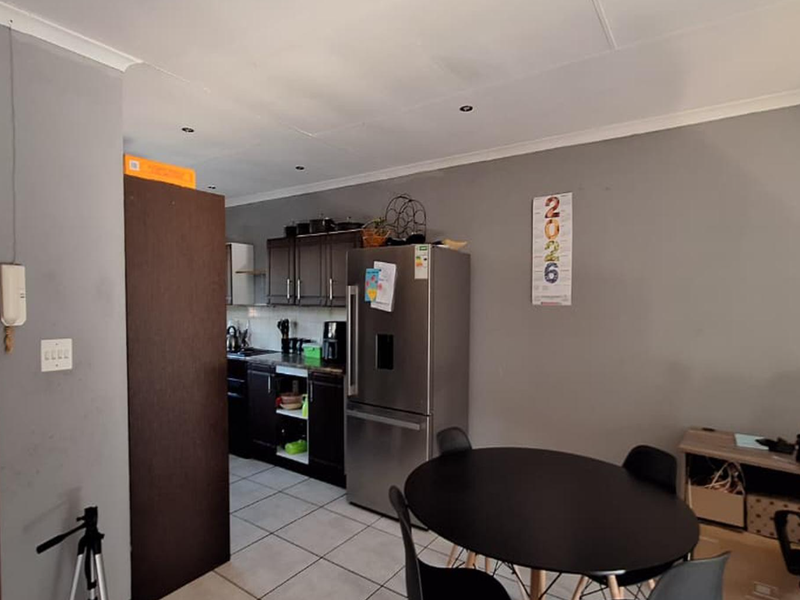 Open plan kitchen and dining area featuring dark cabinetry, tiled flooring, and recessed lighting, with direct access to an outdoor space.