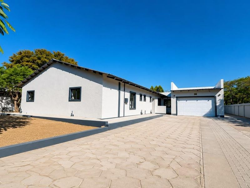 Front view of a well-maintained single-story house featuring a paved driveway, attached garage, and clean exterior finishes.