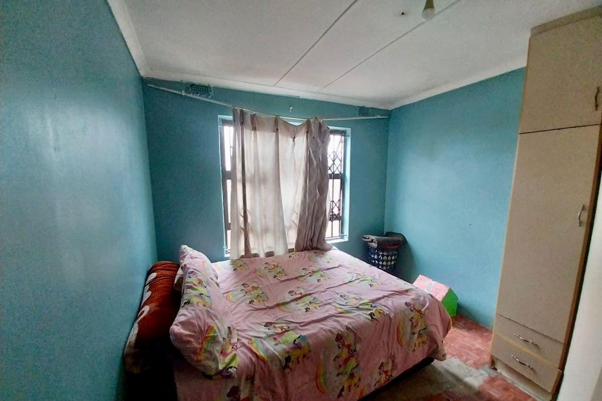 A bedroom featuring blue walls, tiled flooring, and a built-in wardrobe, with security bars installed on the window.