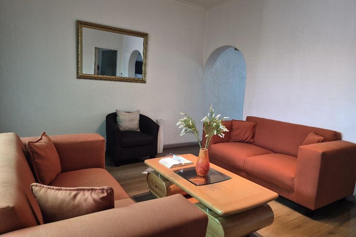 A comfortable living room featuring laminate flooring and a distinctive arched doorway leading to adjacent living spaces.