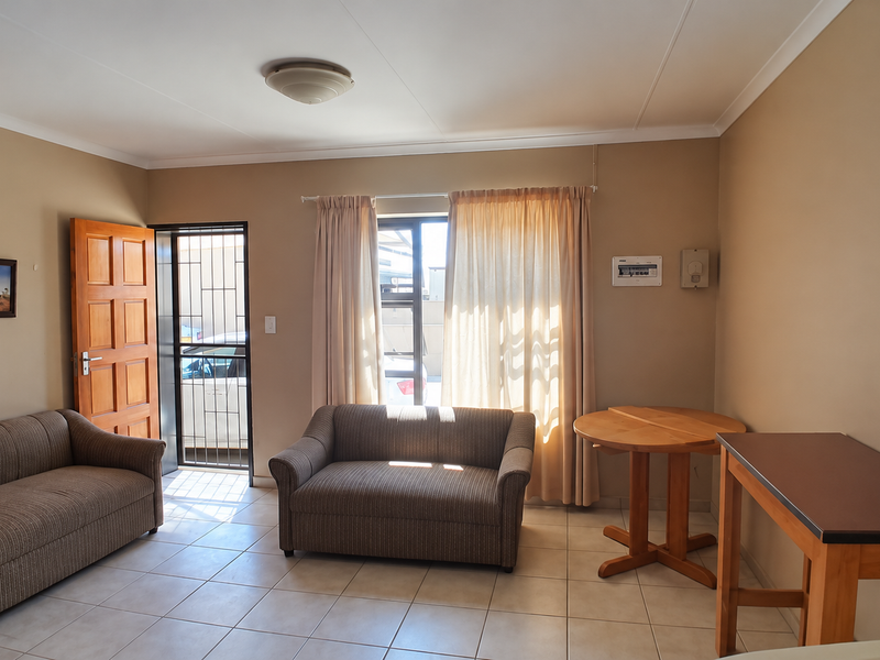 A functional living area featuring tiled flooring, a secure entrance with a security gate, and neutral wall tones, providing a practical and accessible living space.