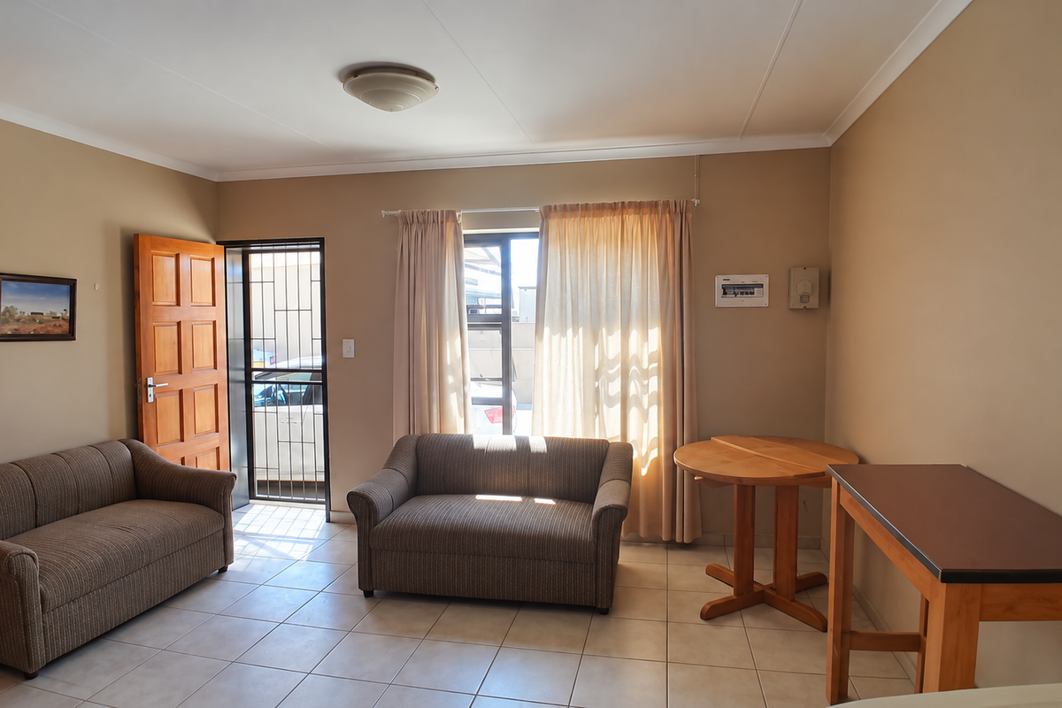 A functional living area featuring tiled flooring, a secure entrance with a security gate, and neutral wall tones, providing a practical and accessible living space.