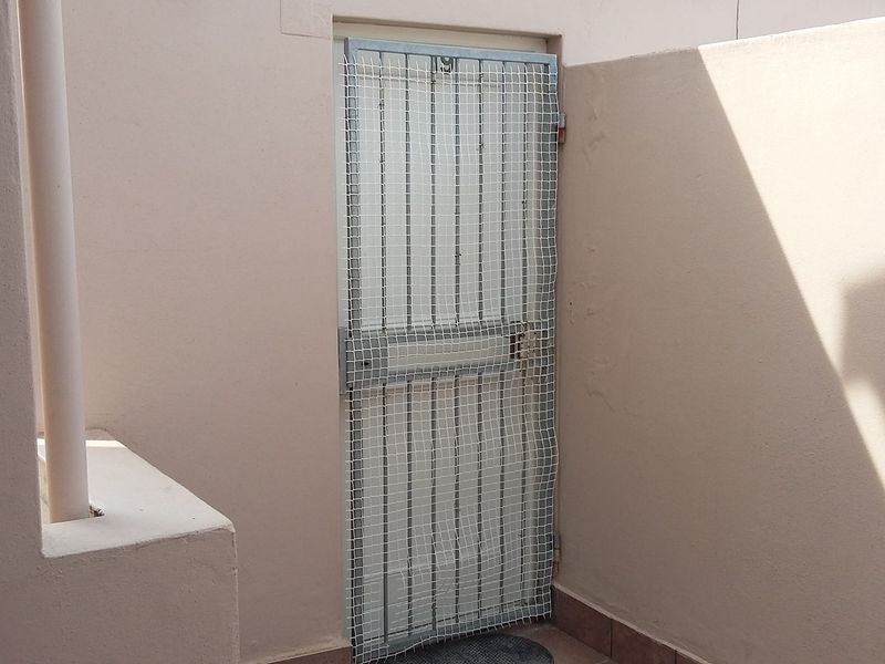 A functional utility area featuring a secure metal gate and exterior masonry walls.