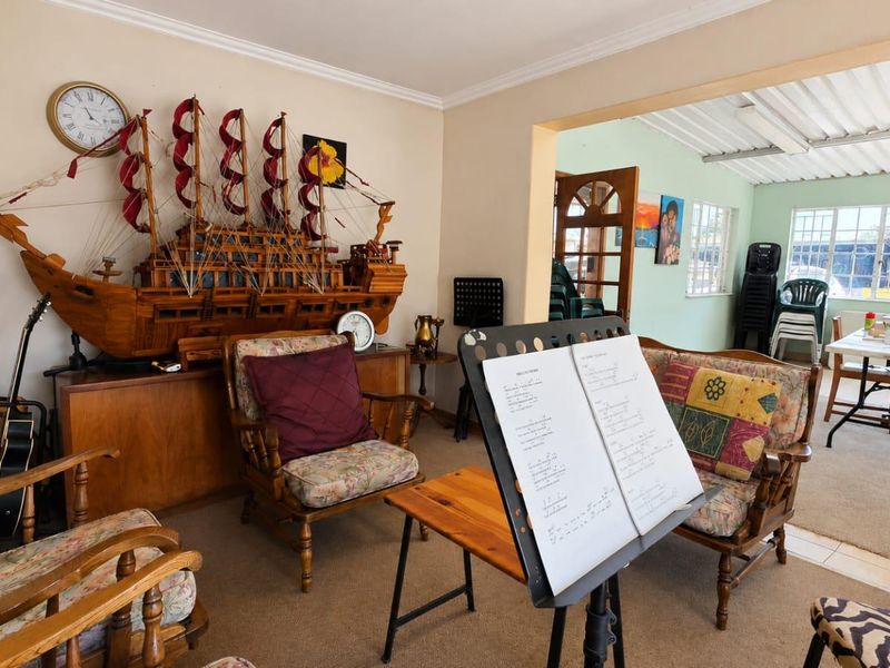 Open plan living area featuring carpeted and tiled flooring, connecting to an adjacent sunroom or dining space with large windows.
