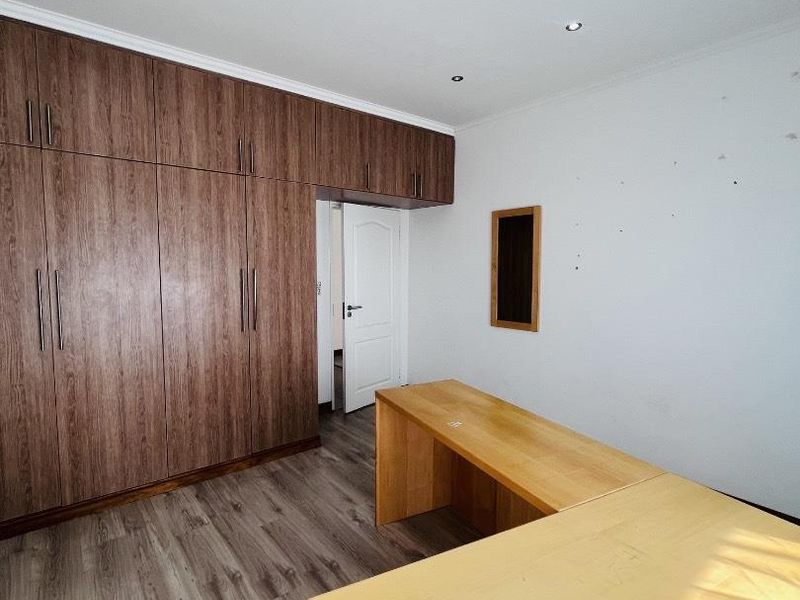 Bedroom featuring extensive built-in wooden cupboards, laminate flooring, and recessed lighting. The space includes a built-in desk unit.