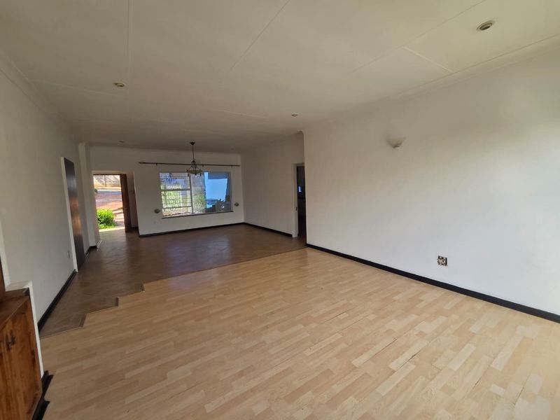 Spacious open-plan living area featuring light laminate flooring, recessed lighting, and a stepped transition between zones, offering a blank canvas for interior design.