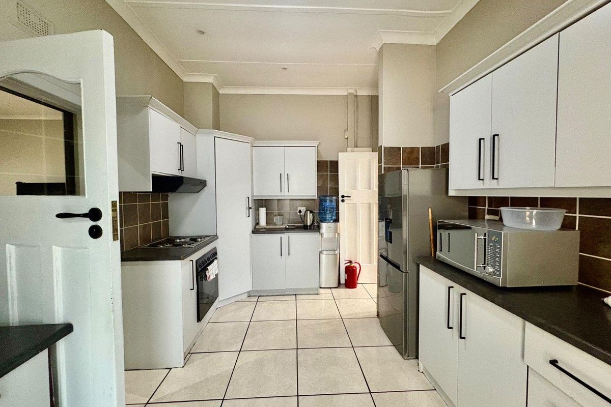 A functional kitchen featuring white cabinetry, dark countertops, tiled backsplash, and tiled flooring, providing a clean and practical workspace.