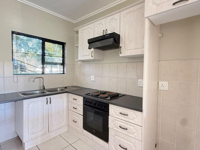 A functional kitchen featuring light-toned built-in cabinetry, dark countertops, a built-in oven with hob, and a tiled backsplash.