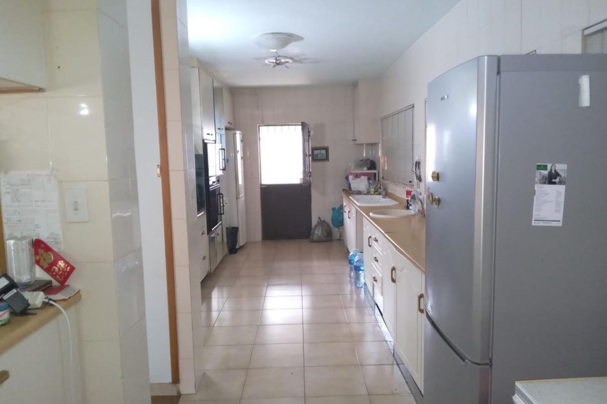 A functional galley-style kitchen featuring tiled flooring, built-in cabinetry, and integrated appliances, leading to an exterior door.