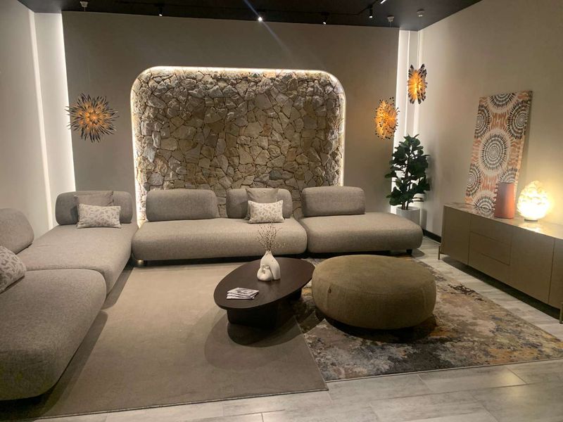 Modern living area featuring a prominent stone accent wall with integrated recessed lighting and sleek tiled flooring.