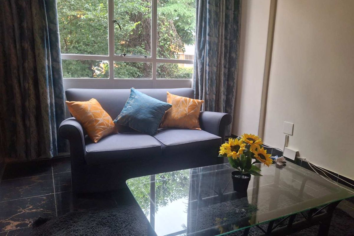 A cozy living room area featuring large windows that provide natural light and views of the surrounding greenery.