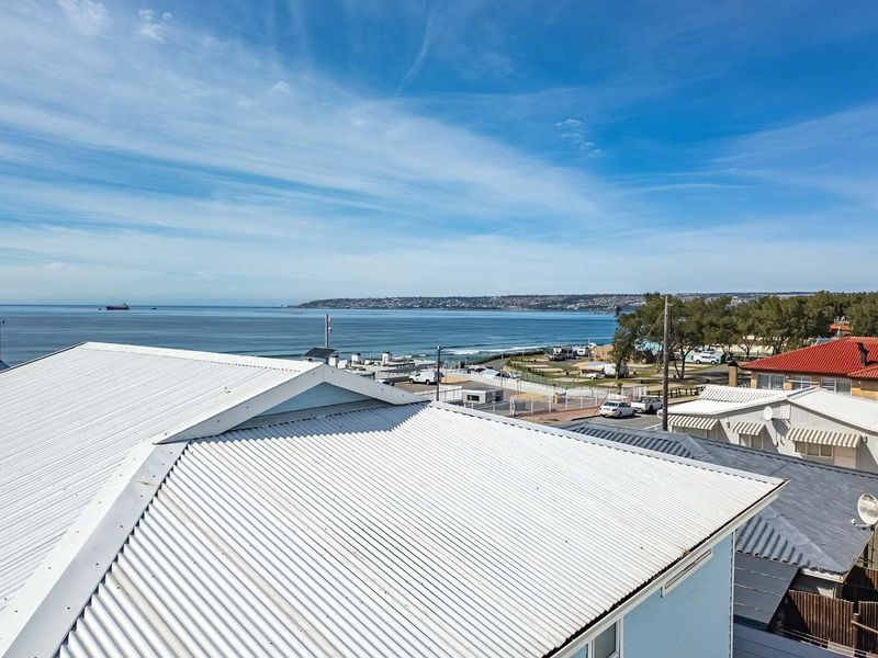Elevated view overlooking the coastline, beach, and surrounding residential neighborhood, featuring a clear perspective of the ocean and horizon.