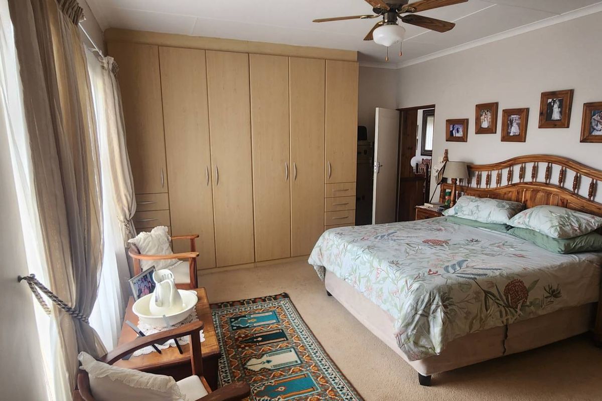 Spacious bedroom featuring built-in wooden cabinetry, neutral carpeting, and a ceiling fan, offering a comfortable and functional living space.