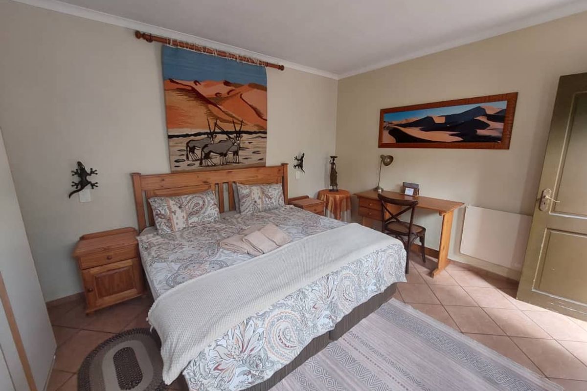 A comfortable bedroom featuring tiled flooring, neutral wall tones, and a classic wooden door, providing a functional and inviting guest space.