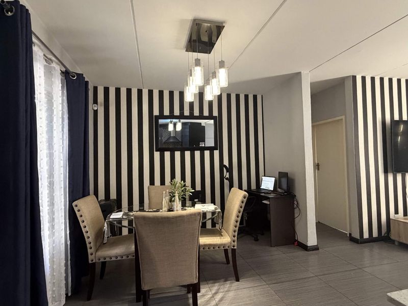 Open-plan living and dining area featuring tiled flooring, modern pendant lighting, and a distinct striped feature wall.