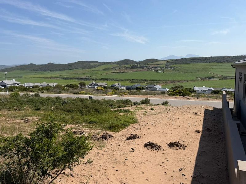 A scenic view overlooking the surrounding landscape, rolling hills, and neighboring residential properties from the vacant residential plot.